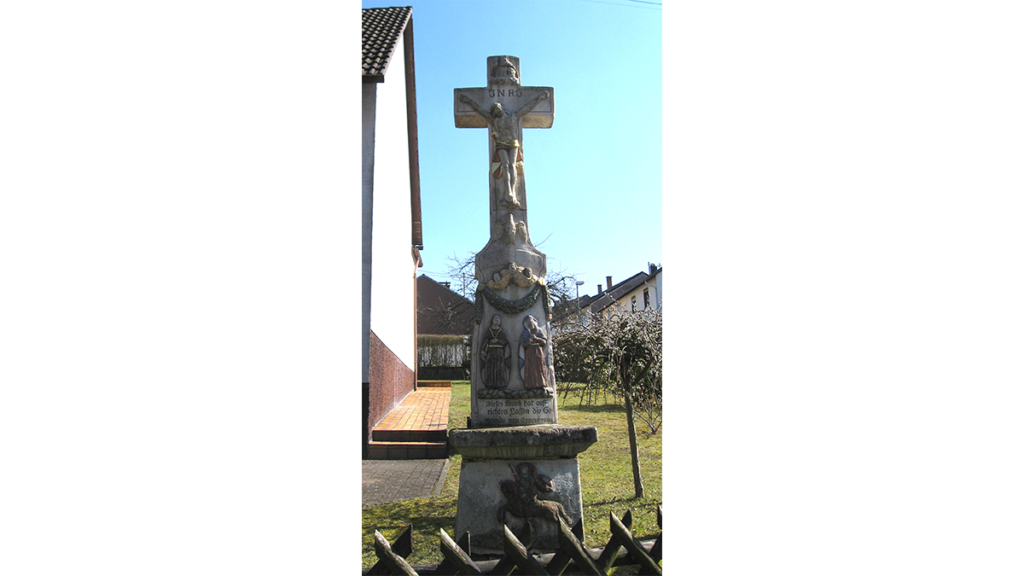 ein massives Steinkreuz neben einer Hauswand in Eppingen.Eine Sehenswürdigkeit im Pfälzerwald