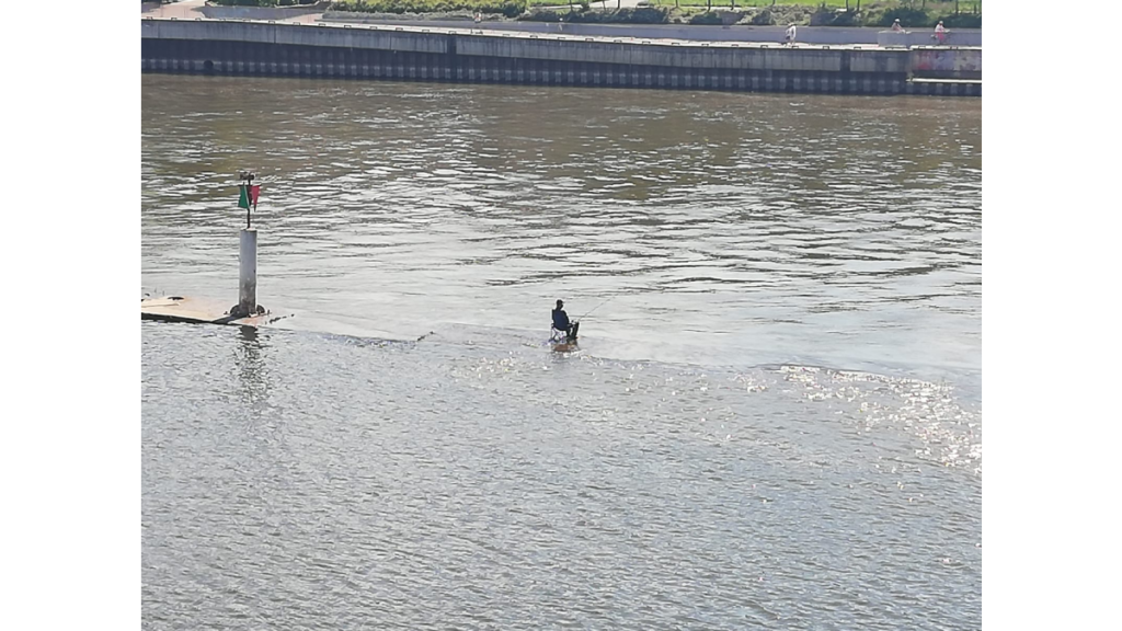 Ein Angler sitzt in der Oder genau an der alten Grenze