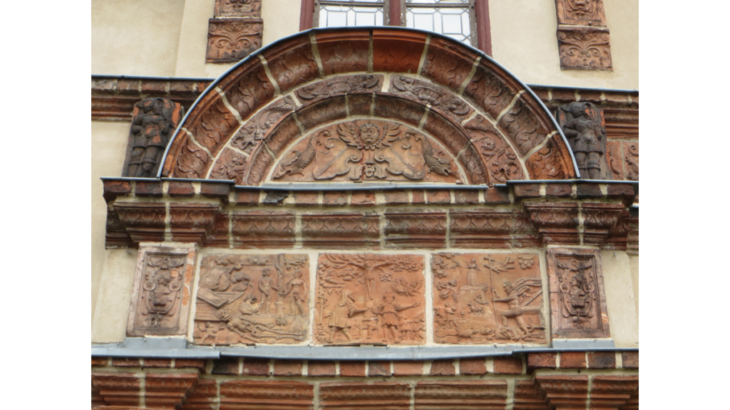 Der Bogen über einem Portal ist mit verschiedenen Terrakotten verziert