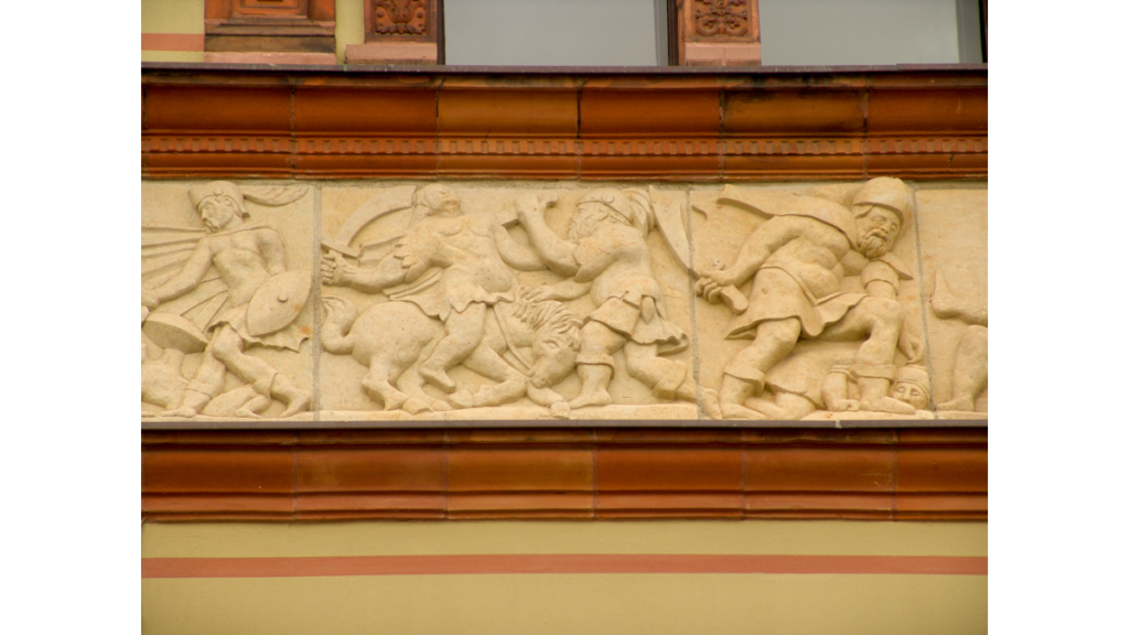 Ein Relief am Wismarer Fürstenhof, das Kämpfende in historischer Kleidung zeigt