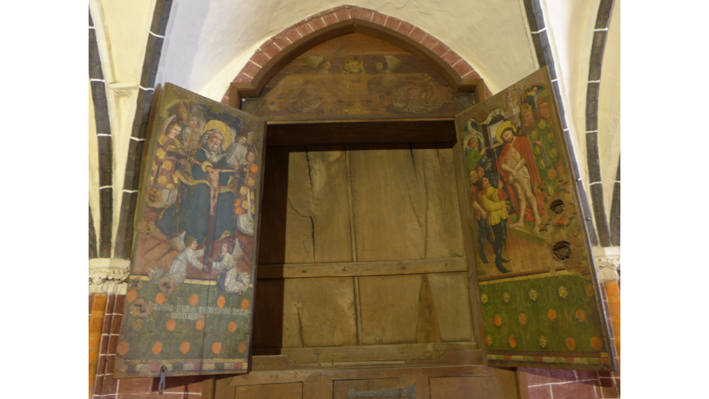 Ein hölzener Schrein mit zwei Flügeln und bemalten Heiligenfiguren auf den Türen