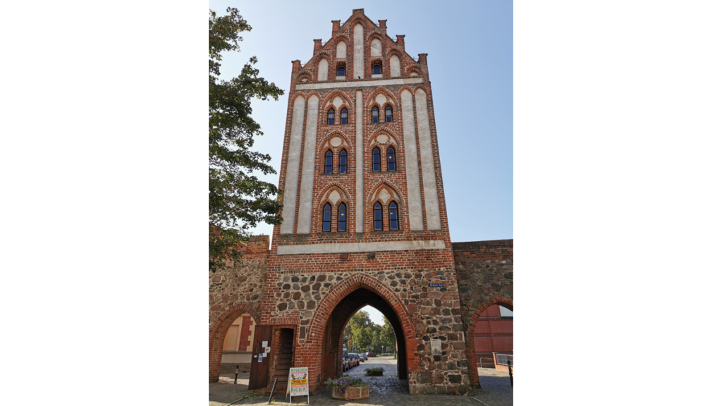Ein mittelalterliches Stadttor, das sich lang über den Torbogen hochzieht