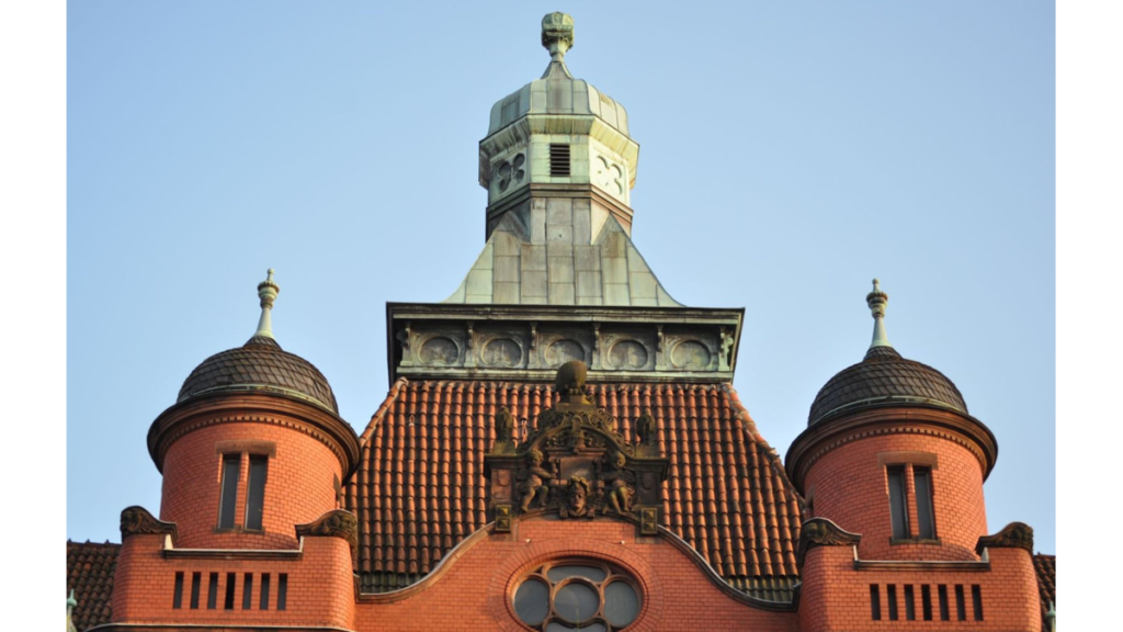 Das Dach des mittleren Teils des Rathauses hat einen mittleren größeren Turm und zwei kleine runde jeweils an der Seite