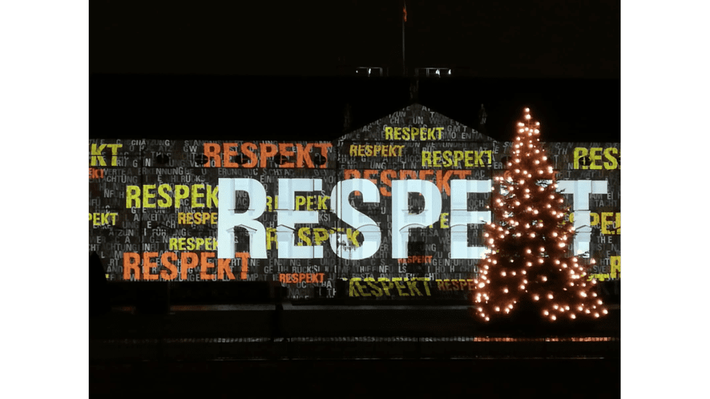 Der Schriiftzug "Respekt" ist auf das weiße Schloss Bellevue projiziert. Im Vordergrund steht ein Tannenbaum