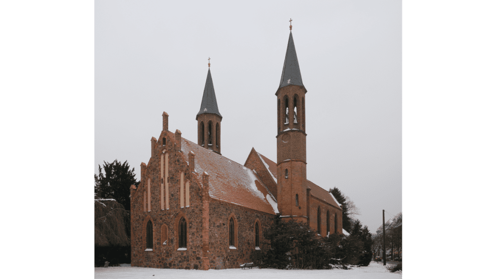 Die aus rötlichem Stein gebaute Kirche Zu den vier Evangelisten besitzt zwei schmale Türme
