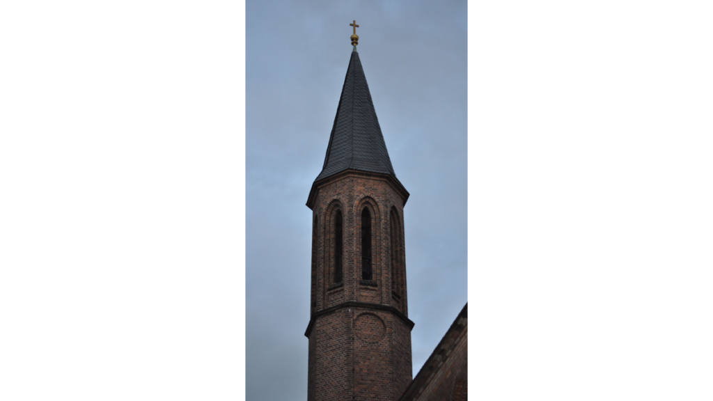 Ein spitzer Turm an der Pfarrkirche in Pankow