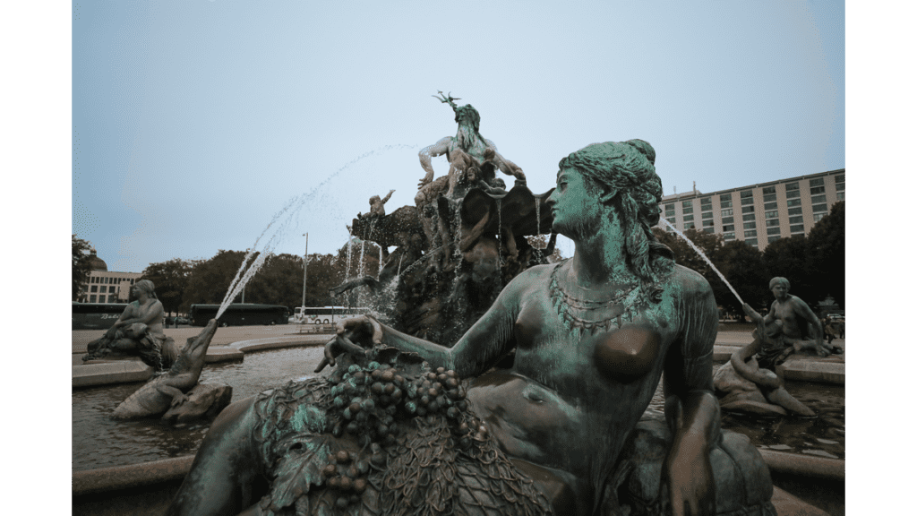 Eine Figurengruppe in einem Brunnen, dem Neptunbrunnen.Im Vordergrund sitzt eine Flussgöttin, dahinter speien Krokodile Wasser. Auf der obersten Ebene sitzt der Meeresgott Neptun mit seinem Dreizack.