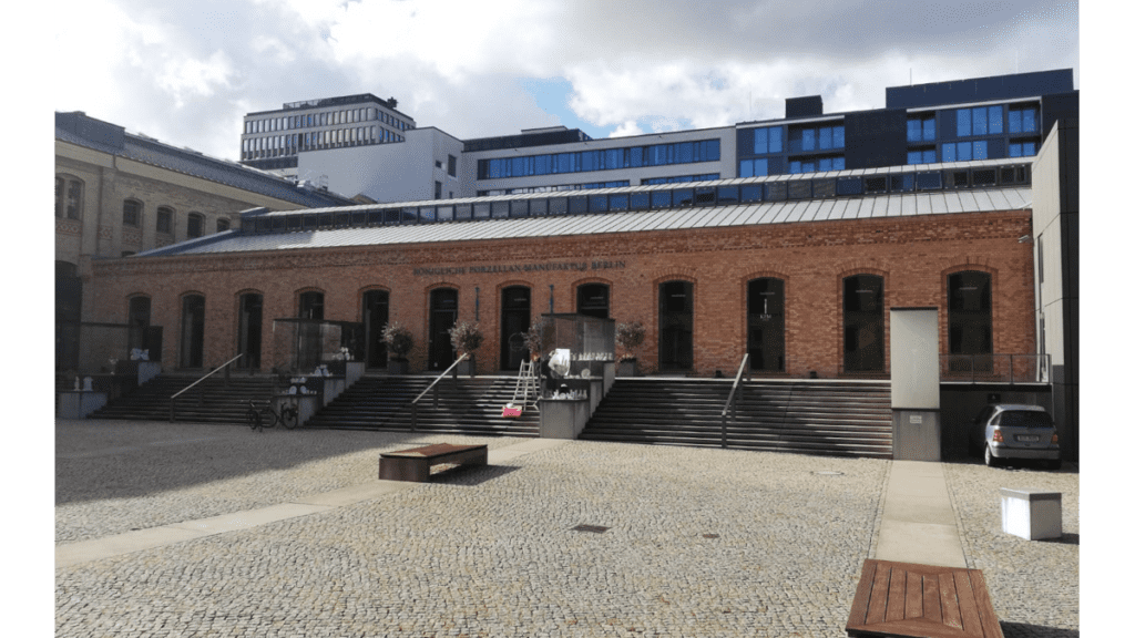 Ein langgezogenes Fabrikgebäude von außen, das die Königliche Porzellan Manufaktur in Berlin beinhaltet