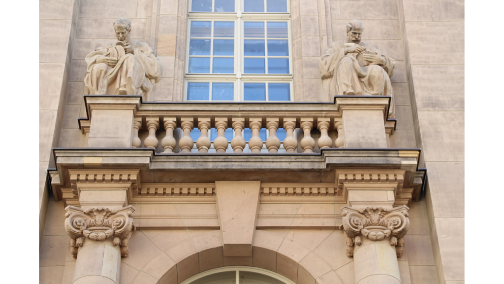 Ein Detail der Aussenfassade der Stattsbibliothek, die im neobarocken Stil gehalten ist. Zwei klassische Figuren beschäftigen sich mit Büchern und Schriften.