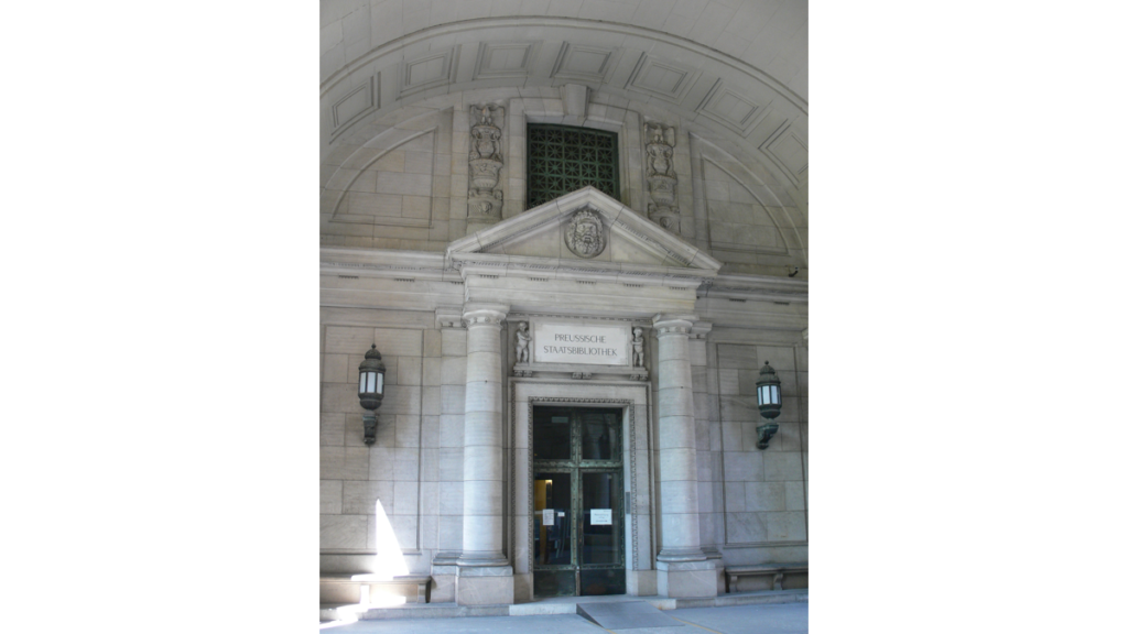 Ein von zwei Säulen gestütztes Portal, das der Durchgang zur Staatsbibliothek ist. Über der Tür steht "Preussische Staatsbibliothek"