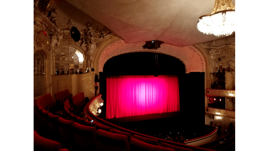 Ein pink angestrahlter Vorhang vor der Bühne in der Komischen Oper