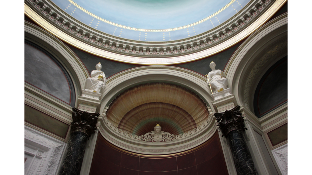 Eine halbrunde Einfassung unter dem Kuppeldach in der Alten Nationalgalerie. Darin ist eine Büste, die rechts und links von weiteren Statuen eingefasst wird.