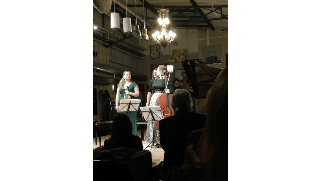 Drei Musikerinnen nehmen auf der kleinen Bühne des Pianosalons Christophori den Applaus des Publikums entgegen.