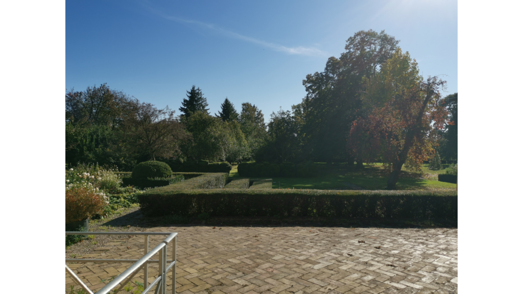 Der Schlosspark Kleßen mit einem Garten links und vielen Bäumen im Hintergrund