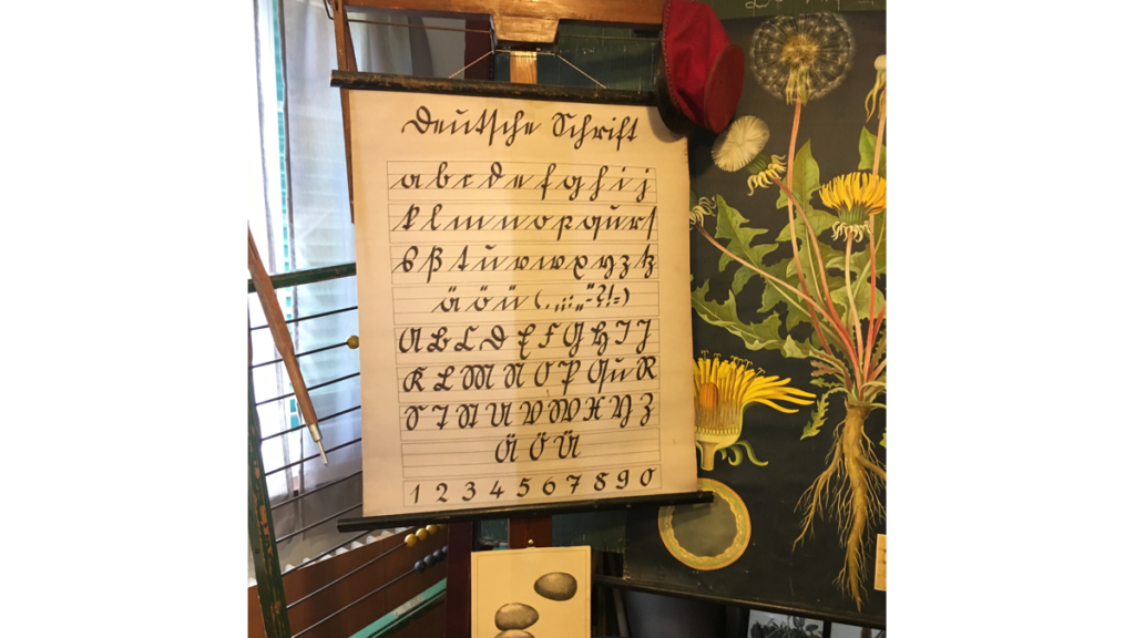 Eine Tafel mit den Buchstaben der Sütterlin-Schrift in einem historischen Klassenzimmer