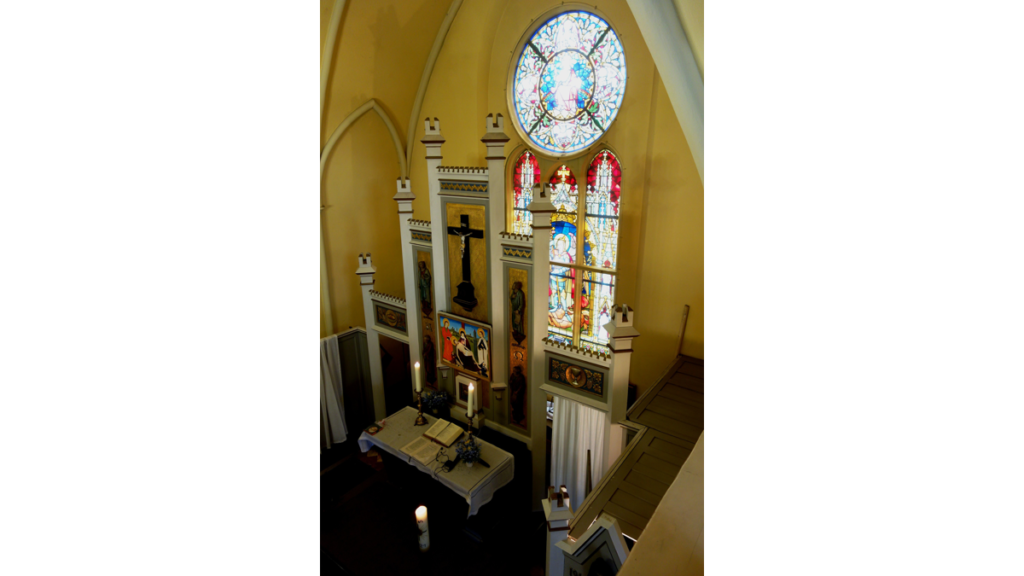 Hinter dem Altar im Inneren der Schinkelkirche befindet sich ein farbiges Chorfenster, ein Geschenk des letzten Deutschen Kaisers Wilhelms II.
