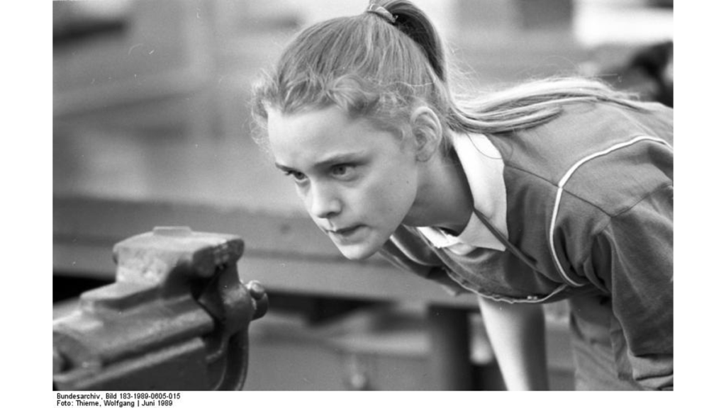 Ein schwarz-weiß Foto aus dem Jahr 1989, in dem ein Mädchen im polytechnischen Unterricht der DDR zeigt