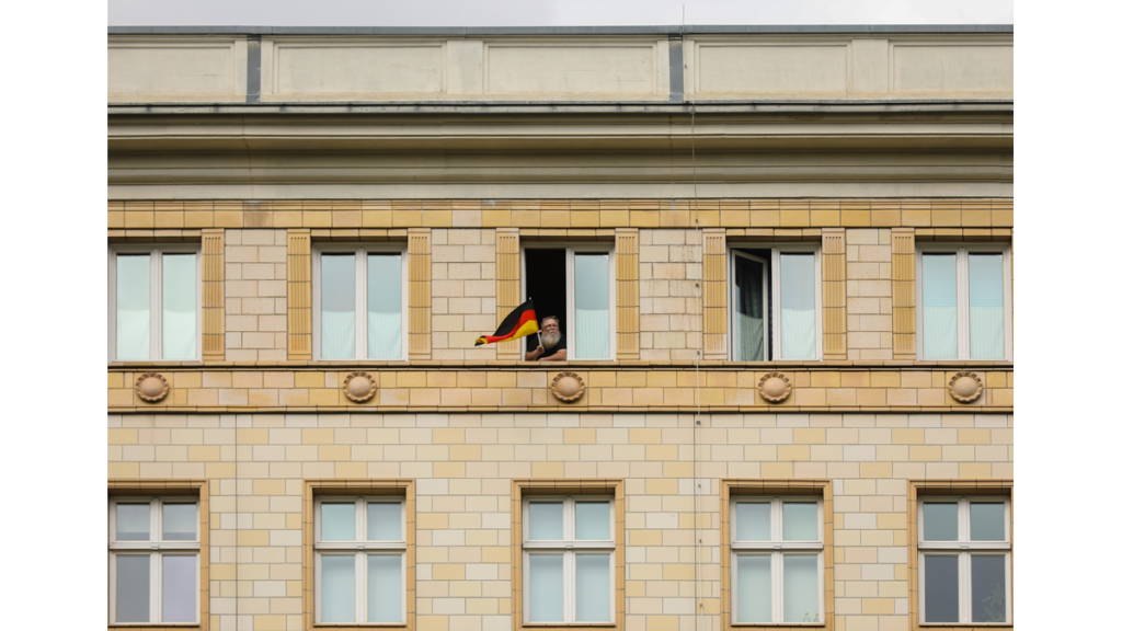 Ein Mann hält eine deutsche Fahne aus einem Gebäude