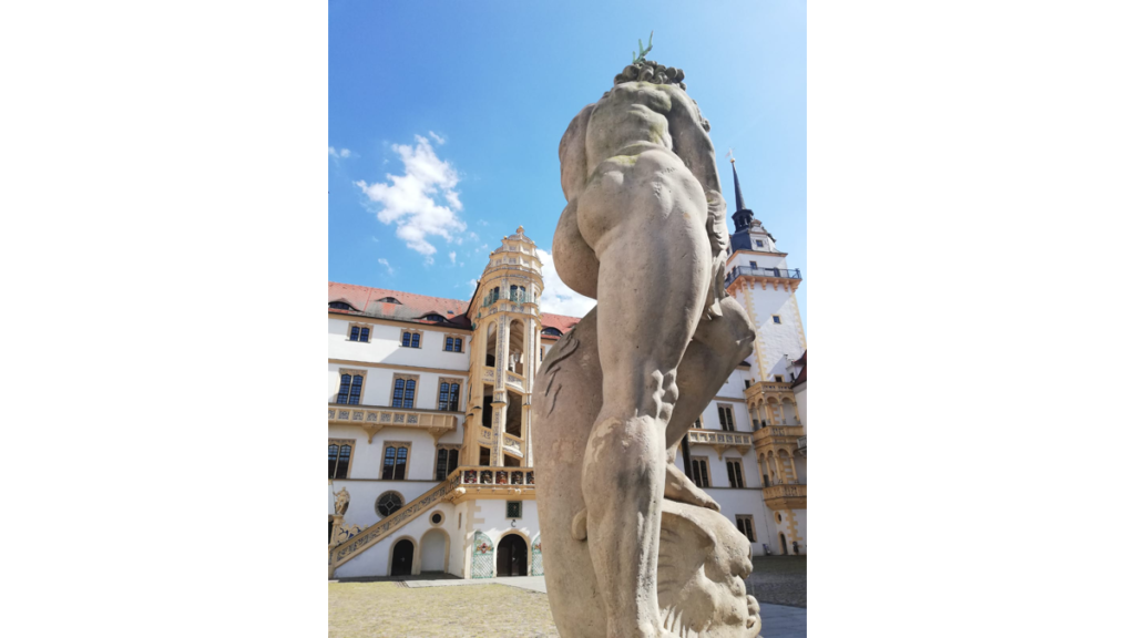 Im Hintergrund die Renaissance Wendeltreppe der Burg Hartenfels, im Vordergrund eine antike Statue