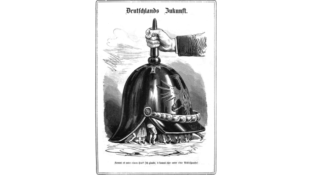 Eine Zeichnung mit dem Titel "Deutschlands Zukunft", auf der Menschen unter einer überdimensionalen Pickelhaube gesteckt werden, darunter steht: "Kommt es unter einem Hut? Ich glaube, 's kommt eher unter eine Pickelhaube"
