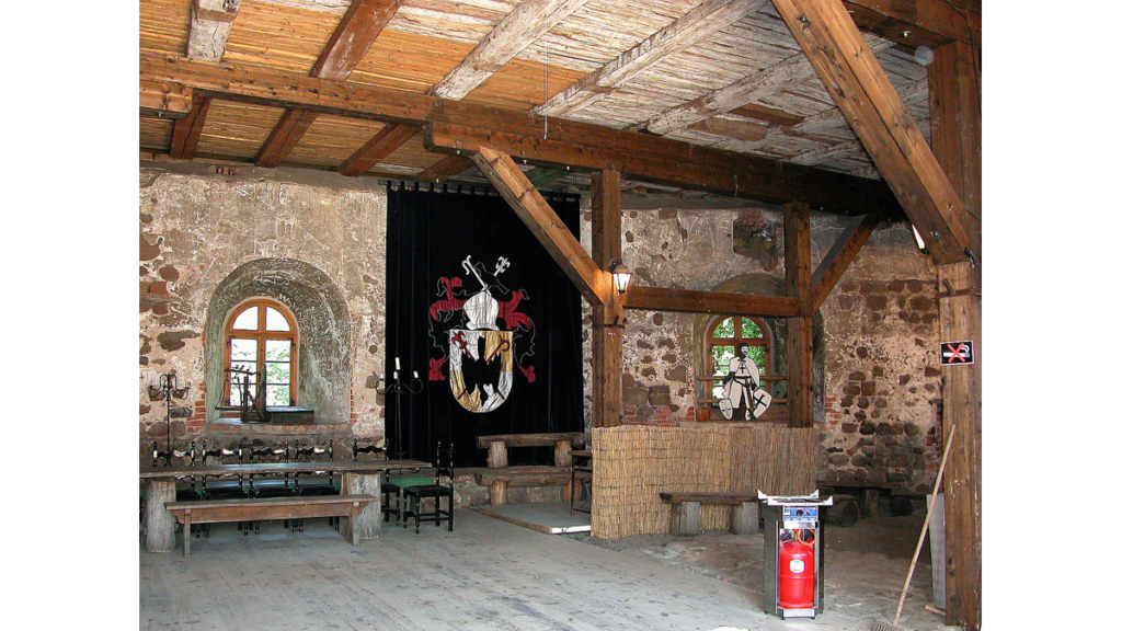 Im Inneren der Burg Rabenstein. Tische stehen vor einem Wappenvorhang.