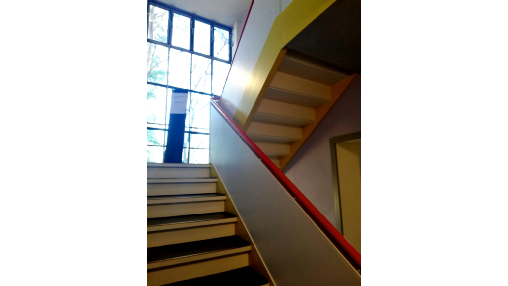 Die Treppe in einem Meisterhaus. Sie ist in den typischen Bauhausfarben rot, blau und gelb gehalten.
