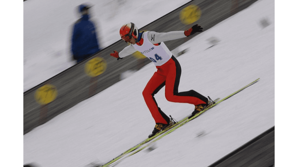 Auf der Skisprungschanze in der Vogtlandarena führt ein Sportler eine Telemarklandung aus.