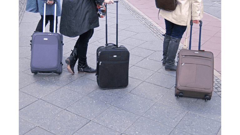 Drei Rollkoffer von Reisenden am Berliner Hauptbahnhof, wie sie sich für eine längere Busreise empfehlen.