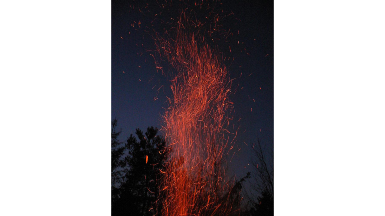 Der Funkenflug eines Feuers vor einem Nachthimmel.
