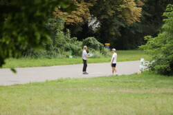 Foto: © Stefan Schaubitzer / comkomm Eine Frau zielt mit ihrem Frisbee auf den zu treffenden Metallkorb, ein Freund schaut zu