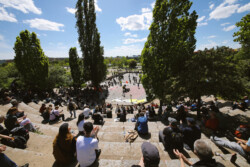 Foto: © Stefan Schaubitzer / comkomm Eine Gruppe Menschen auf einer abfallenden Steintribüne applaudiert einem Sänger, der auf einer Karaokebühne steht.