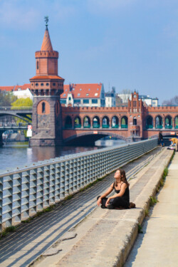 Foto: © Stefan Schaubitzer / comkomm Eine Frau sitzt mit geschlossenen Augen und Kopfhörern vor dem Brückengeländer und genießt die Sonne